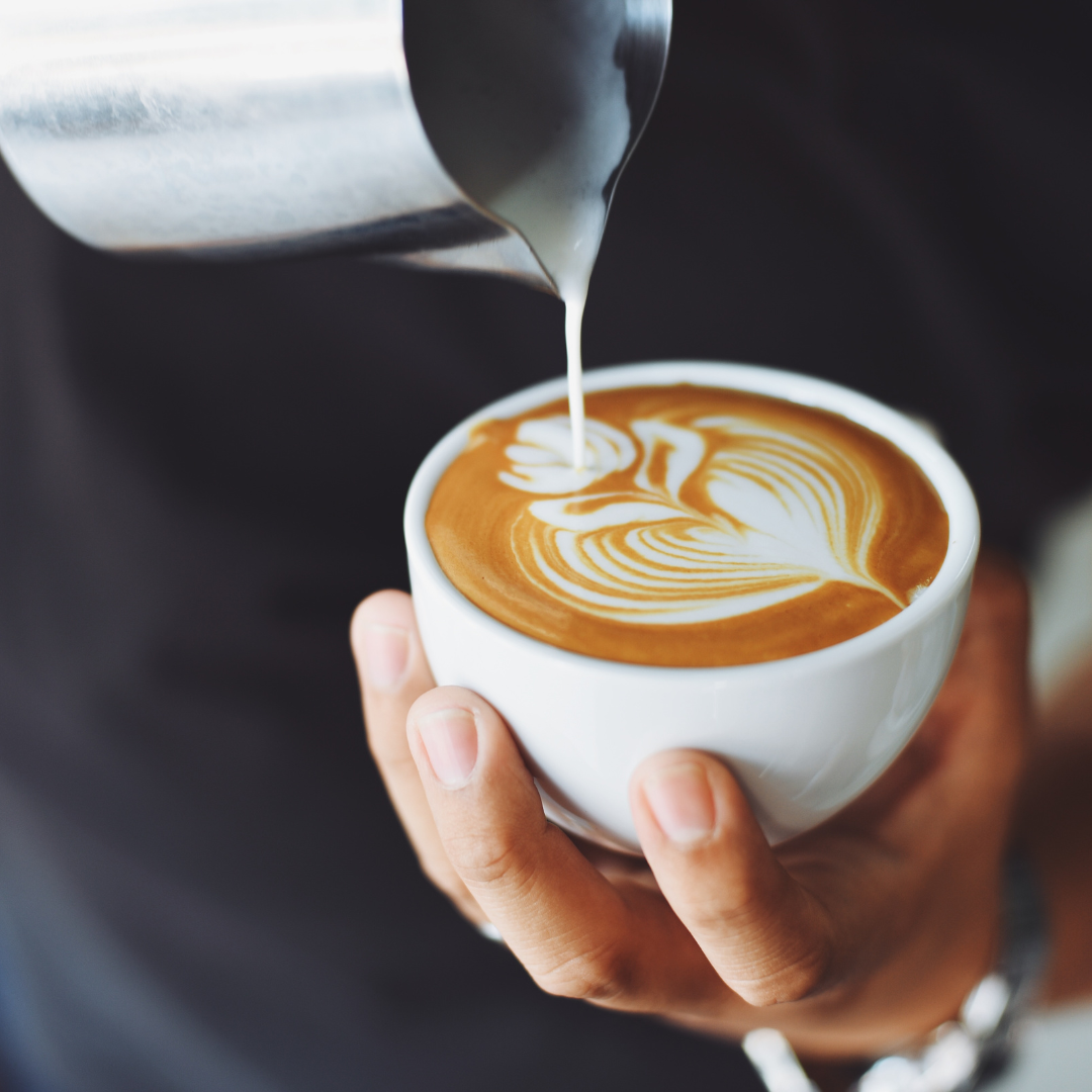 Milk being poured into a cup of coffee to create latte art