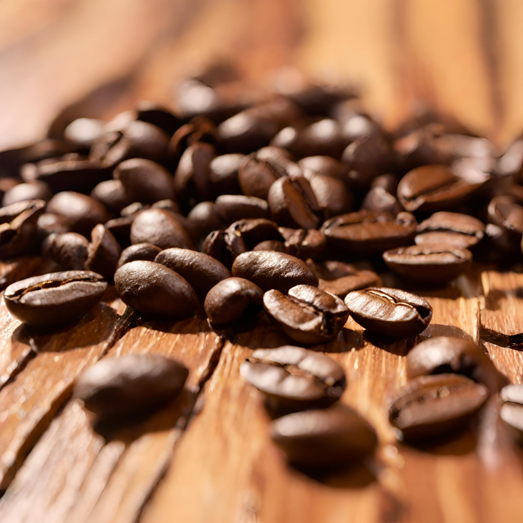 Close-up of freshly roasted coffee beans scattered across a rustic wooden surface, highlighting their rich brown color, natural oils, and textured grain.