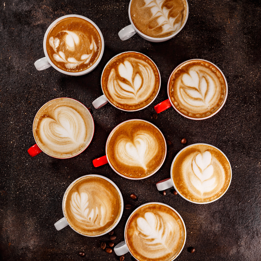 Top view of artisan lattes with heart and leaf latte art in ceramic cups on dark background