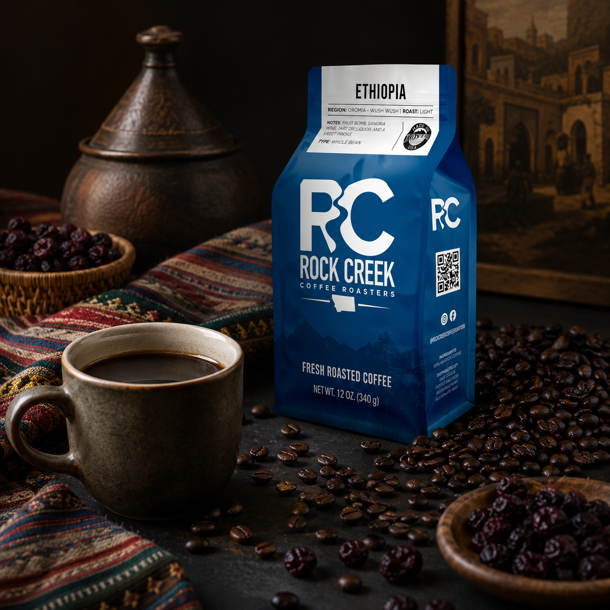 Ethiopian Harrar origin coffee image featuring Rock Creek Coffee Roasters coffee bag, brewed black coffee, roasted coffee beans, dried fruit, and an Ethiopian-inspired background.