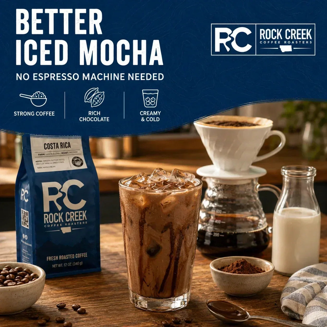 Homemade iced mocha with rich coffee, milk, chocolate, and ice beside Rock Creek Coffee, a pour-over brewer, cocoa powder, and whole coffee beans.