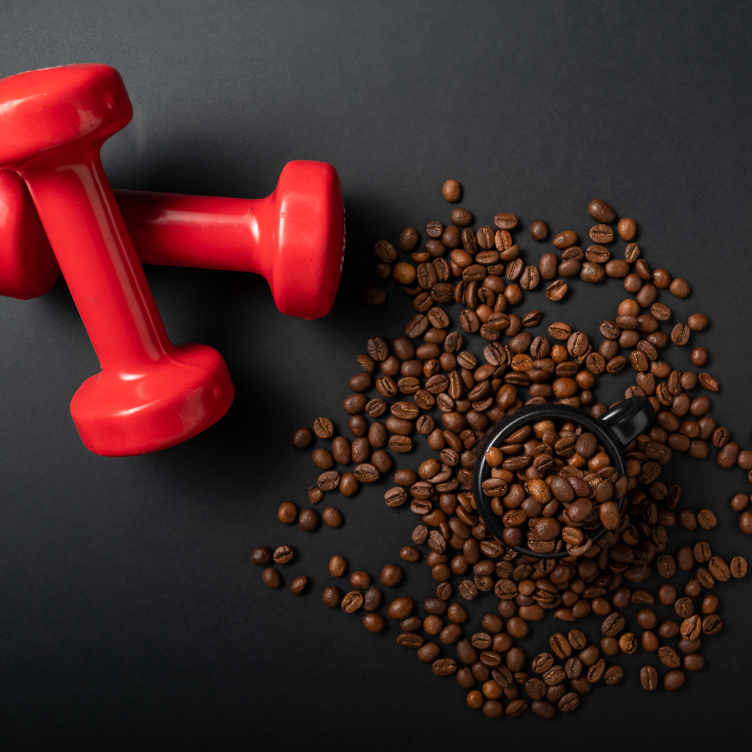 Red dumbbell next to scattered coffee beans and a small cup on a dark background