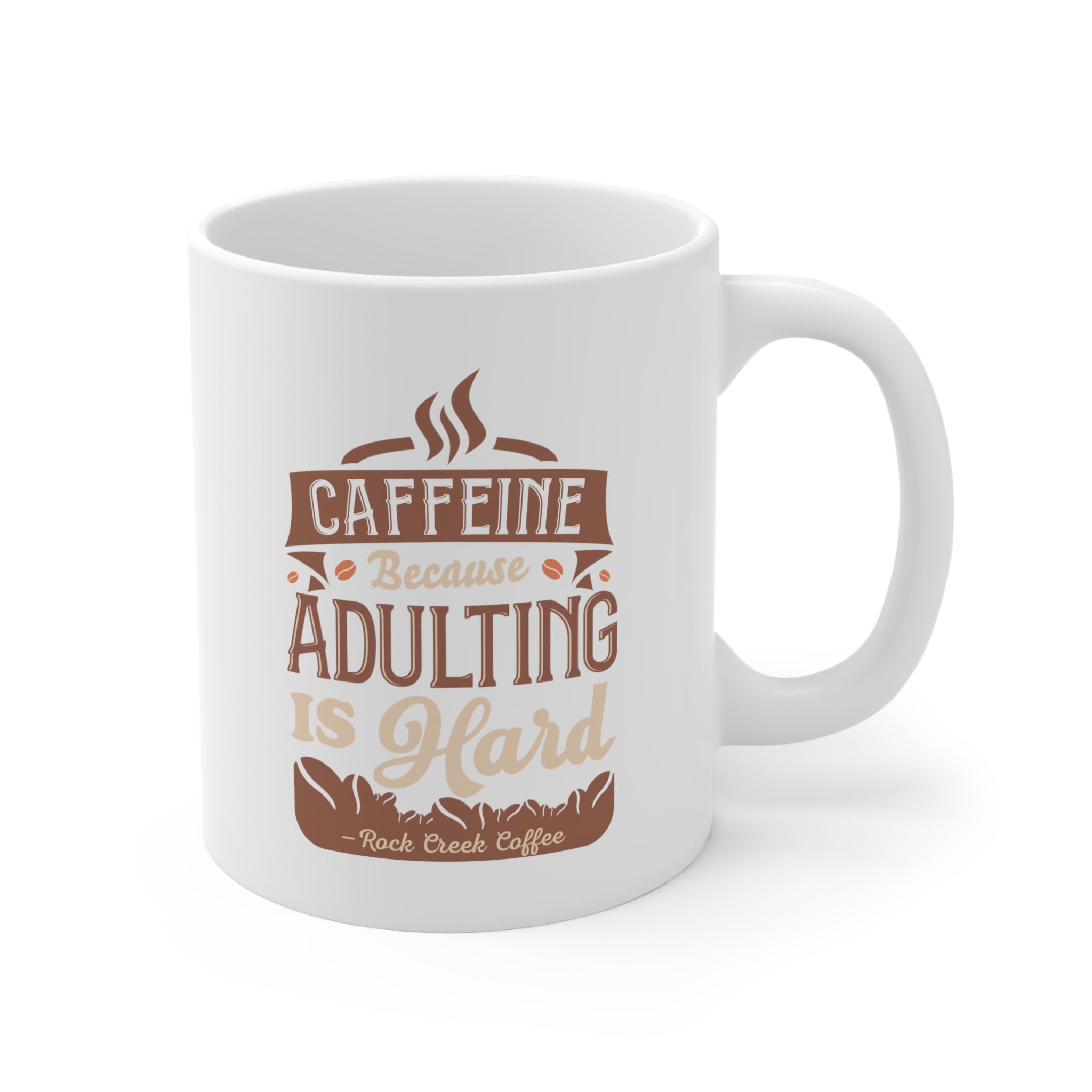 White Rock Creek Coffee mug featuring the phrase “Caffeine Because Adulting Is Hard” in brown and tan lettering with coffee bean graphics.