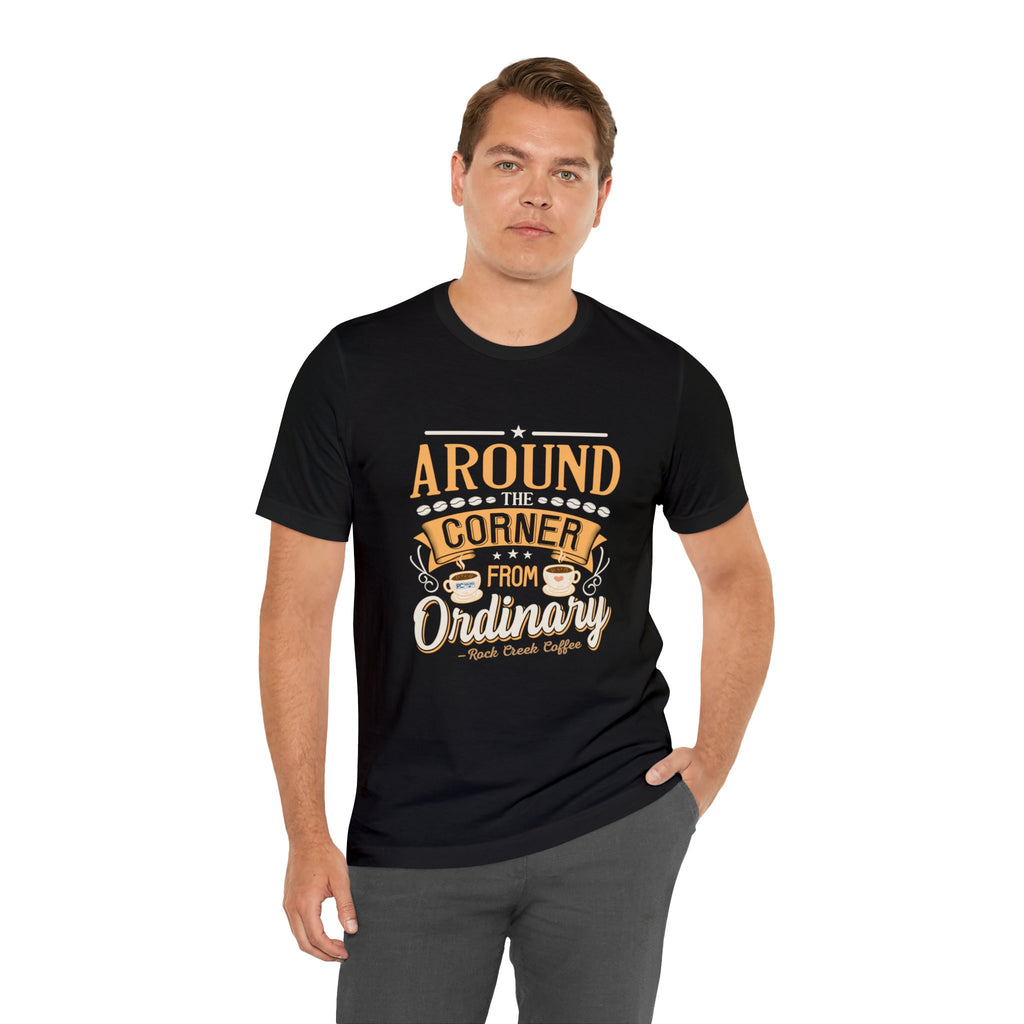 Male model wearing a black Rock Creek Coffee T-shirt featuring the “Around the Corner From Ordinary” graphic print