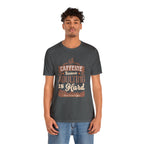Adult man modeling an asphalt short-sleeve T-shirt featuring the “Caffeine Because Adulting Is Hard” graphic in a stacked typographic design, shown against a plain white background.
