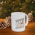 White Rock Creek Coffee mug featuring the phrase “Sippin on Genius Juice” in stylized gray and gold lettering with a small coffee cup graphic, filled with coffee and styled on a wooden surface with pinecones and warm holiday lights in the background.