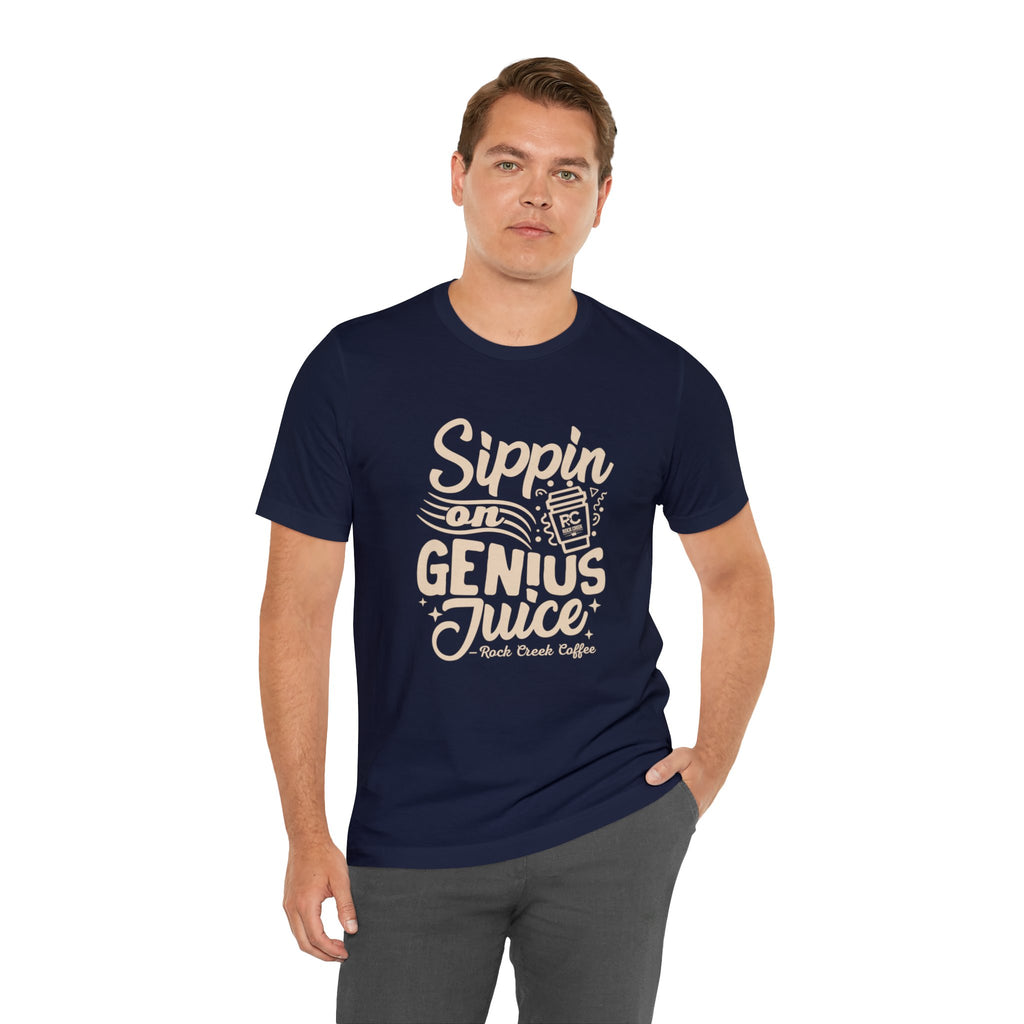 Adult man modeling a navy short-sleeve T-shirt printed with the slogan “Sippin on Genius Juice” and a stylized coffee to-go cup graphic on the front, shown against a plain white background.