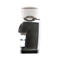 Side profile of the Baratza Forte AP coffee grinder in brushed stainless steel with a clear bean hopper, portafilter holder, and compact base, displayed against a white background.