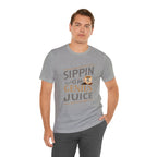 Adult man wearing a heather gray short-sleeve T-shirt featuring the “Sippin on Genius Juice” graphic in bold stacked lettering with a small coffee cup icon, posed against a plain white background.