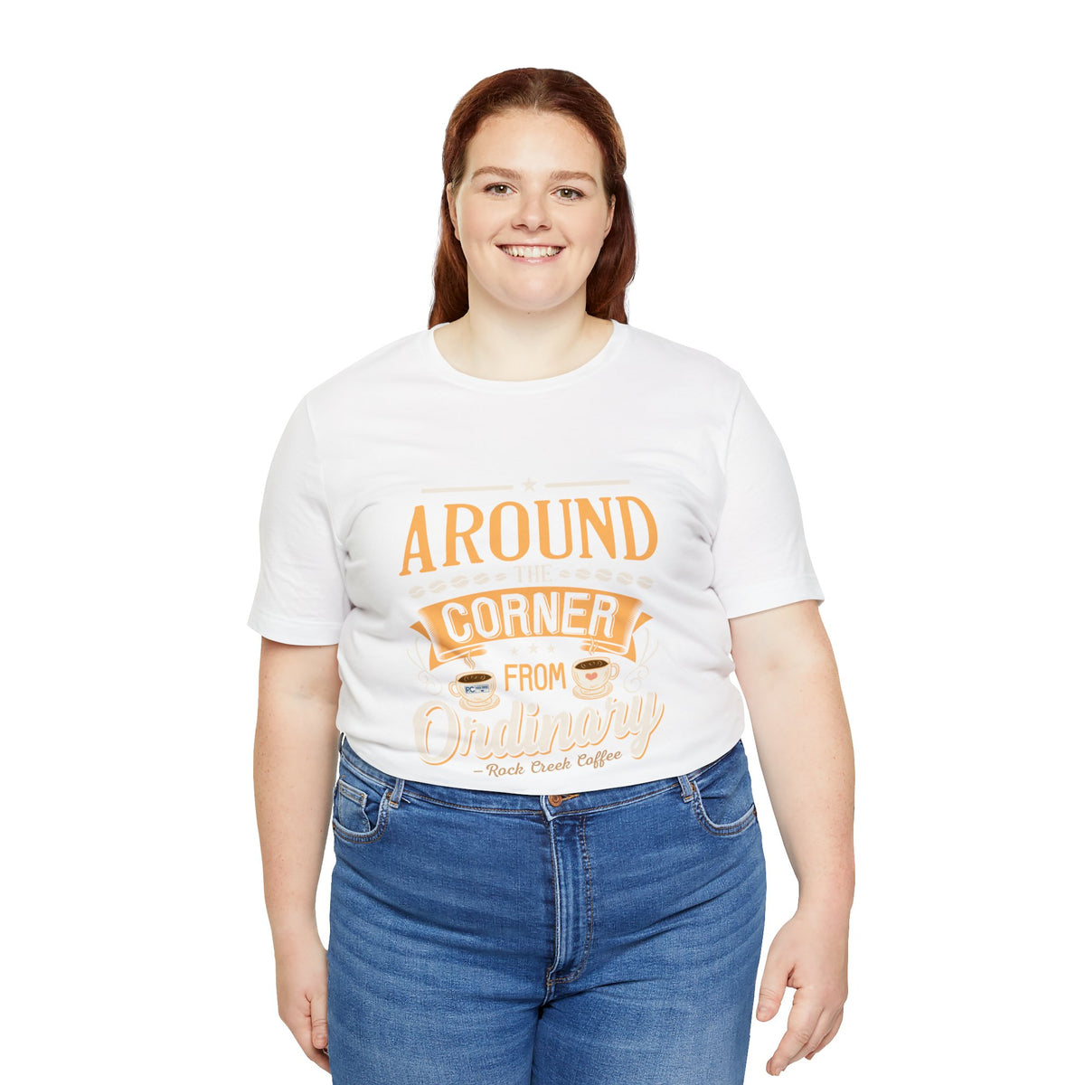 Plus-size female model wearing a white Rock Creek Coffee T-shirt featuring the “Around the Corner From Ordinary” graphic print