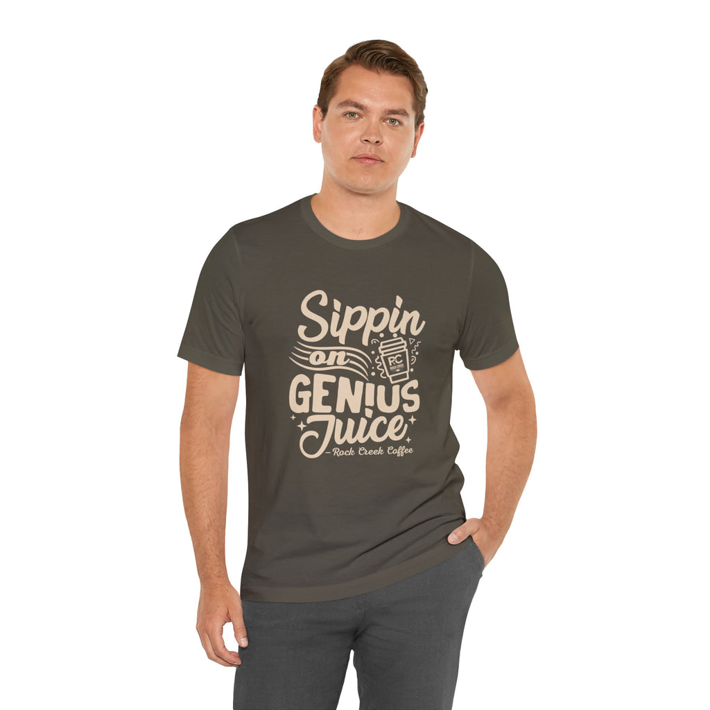 Adult man modeling an olive green short-sleeve T-shirt printed with the slogan “Sippin on Genius Juice” and a stylized coffee to-go cup graphic on the front, shown against a white background.