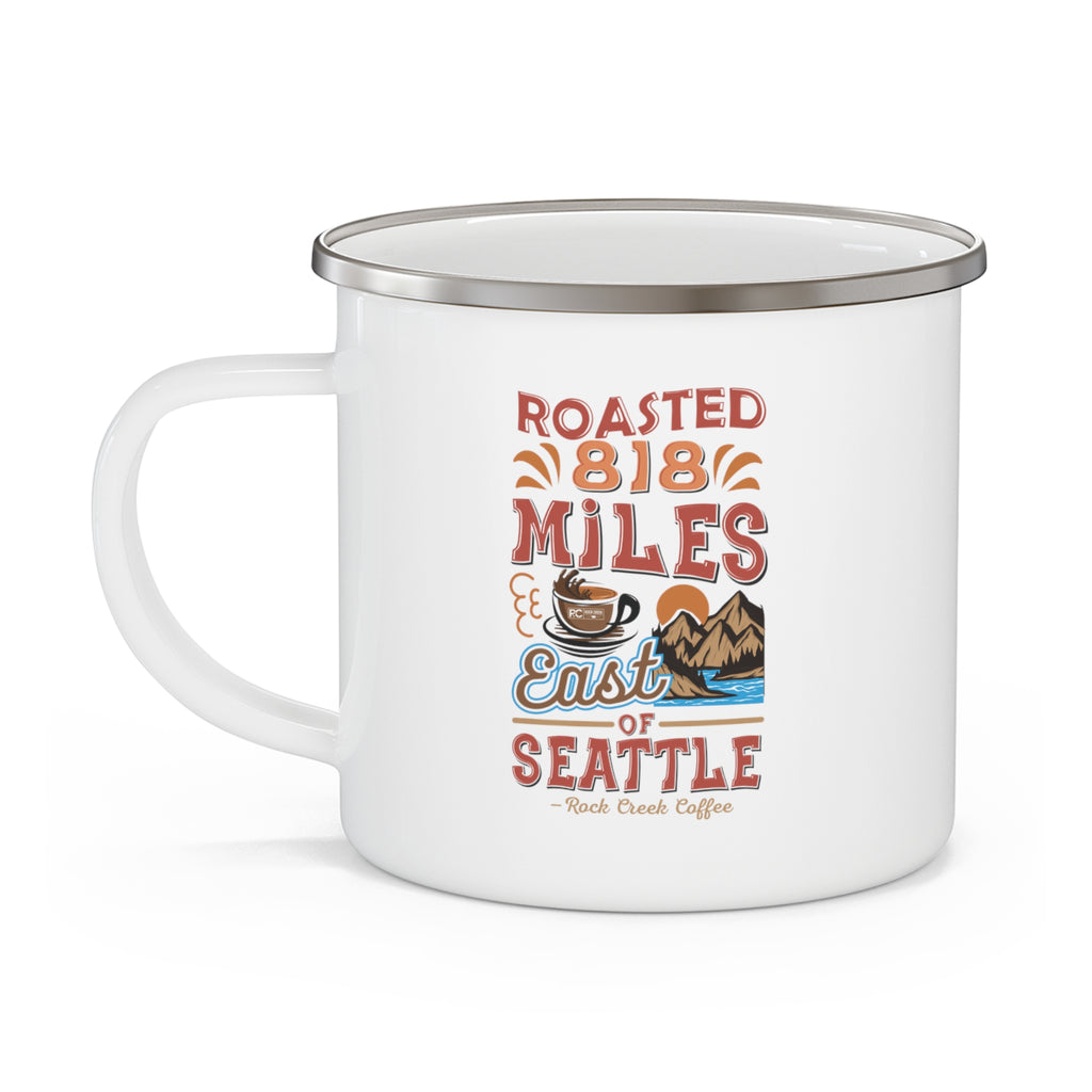 White enamel-style coffee mug with silver rim and side handle featuring a colorful “Roasted 818 Miles East of Seattle – Rock Creek Coffee” design with a coffee cup and mountain illustration, displayed against a white background.