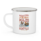 White enamel-style coffee mug with silver rim and side handle featuring a colorful “Roasted 818 Miles East of Seattle – Rock Creek Coffee” design with a coffee cup and mountain illustration, displayed against a white background.