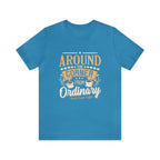 Aqua short-sleeve T-shirt displayed flat against a plain white background, featuring the phrase “Around the Corner from Ordinary” in a bold coffee-themed typographic design with Rock Creek Coffee branding below.