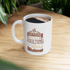 White Rock Creek Coffee mug featuring the phrase “Caffeine Because Adulting Is Hard” in brown and tan lettering, filled with coffee and placed on a wooden table with green plants blurred in the background.