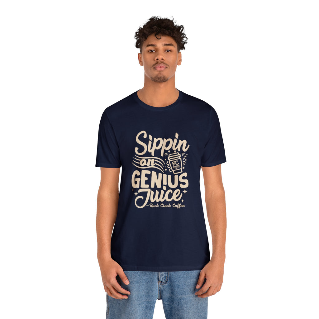 Adult man modeling a navy short-sleeve T-shirt printed with the slogan “Sippin on Genius Juice” and a stylized coffee to-go cup graphic on the front, shown against a plain white background.
