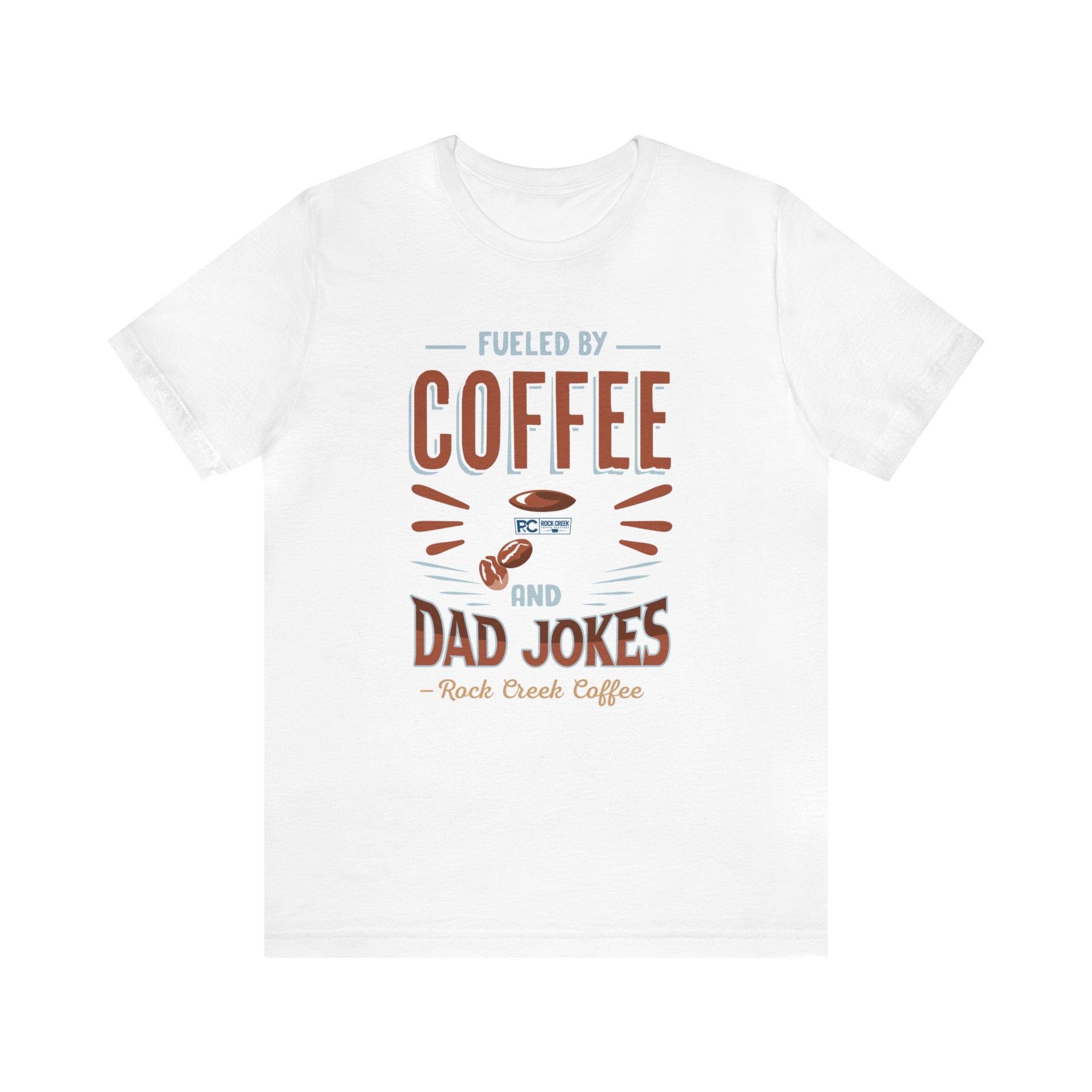White short-sleeve T-shirt displayed flat against a plain white background, featuring the “Fueled by Coffee and Dad Jokes” graphic with a coffee cup illustration and Rock Creek Coffee text below.