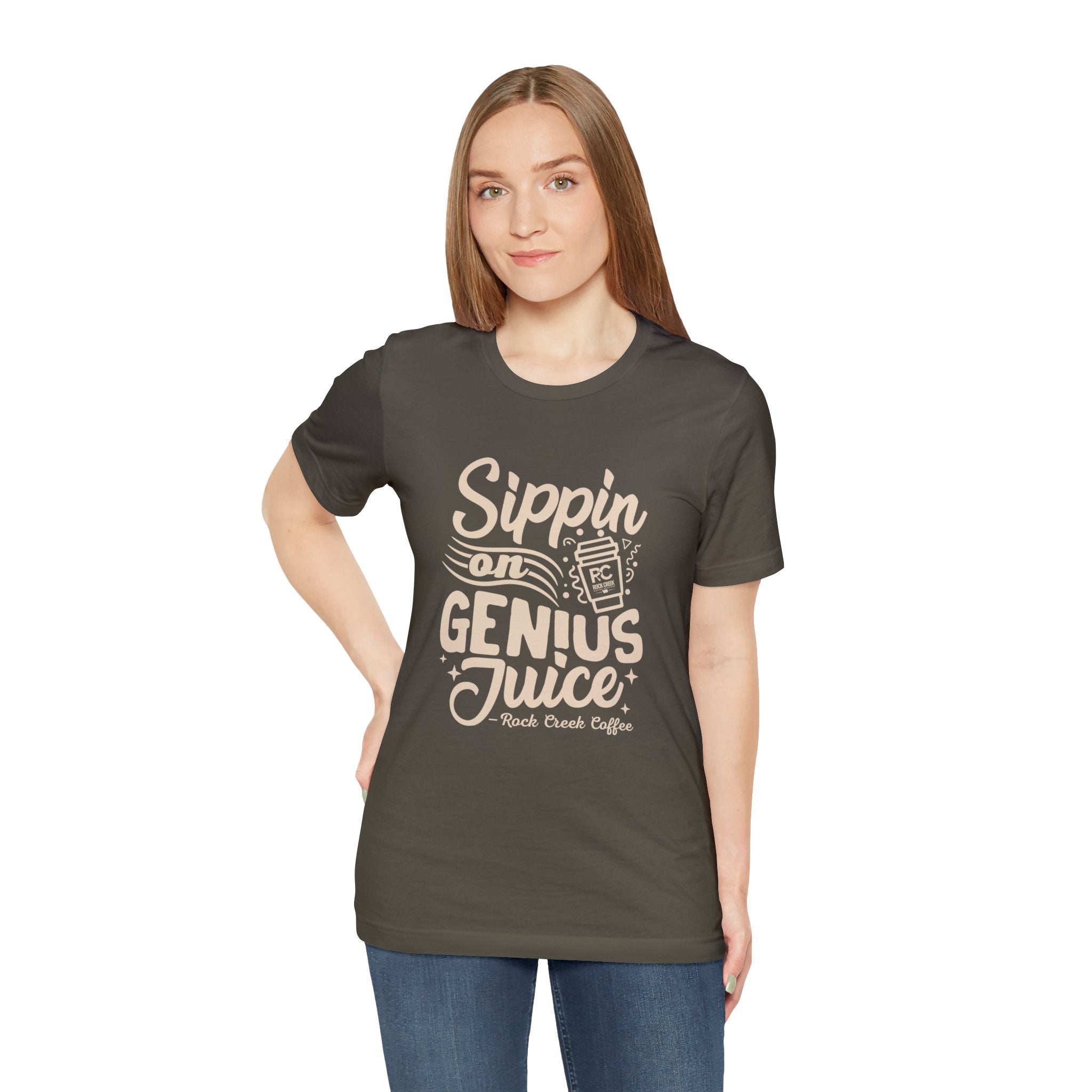 Smiling woman modeling an olive green short-sleeve T-shirt printed with the slogan “Sippin on Genius Juice” and a stylized coffee to-go cup graphic on the front, shown against a plain white background.