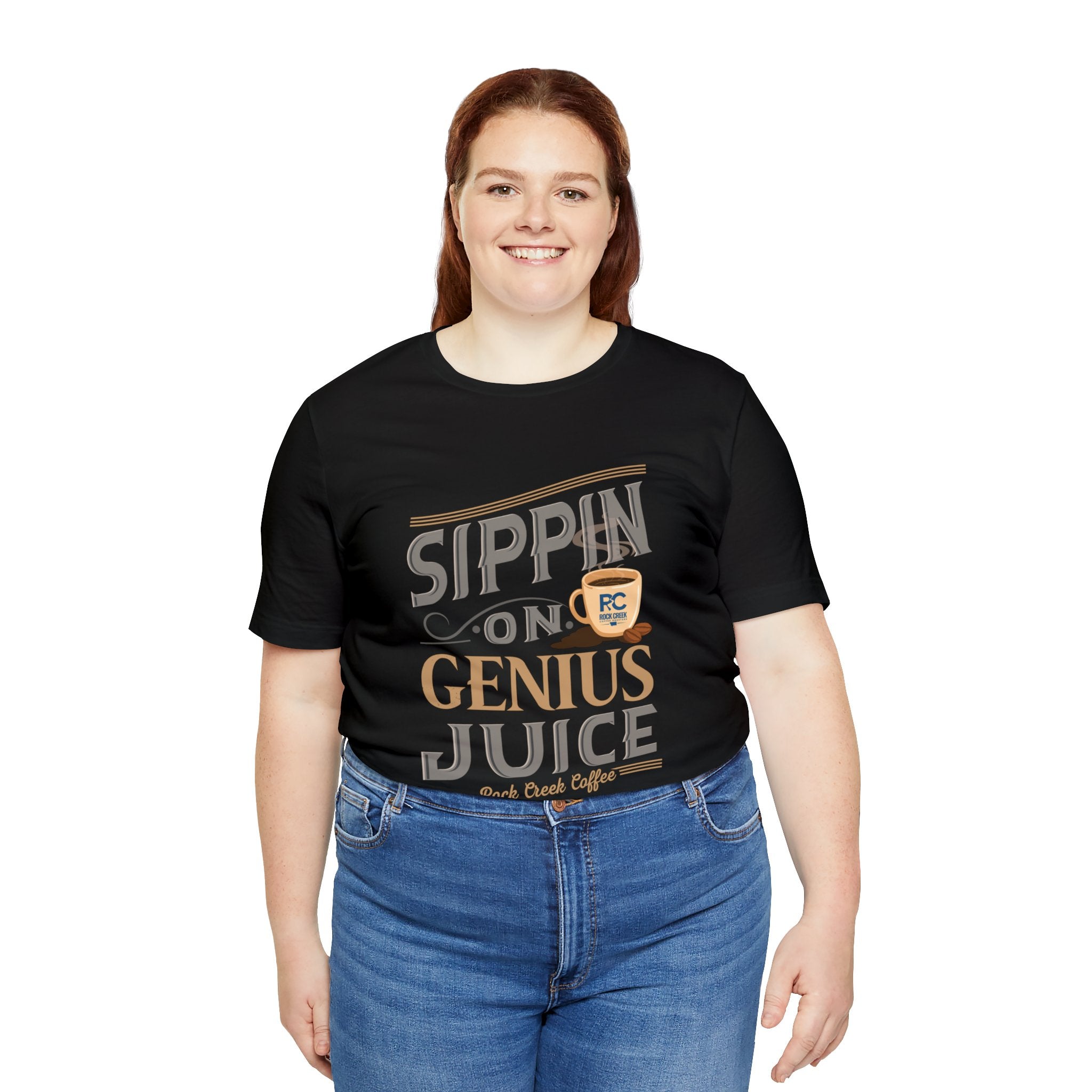 Adult woman smiling while modeling a black short-sleeve T-shirt featuring the “Sippin on Genius Juice” graphic in bold coffee-inspired lettering with a small cup illustration, shown against a plain white background.