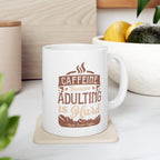 White Rock Creek Coffee mug featuring the phrase “Caffeine Because Adulting Is Hard” in brown and tan lettering, displayed on a kitchen counter with a bowl of lemons and avocados in the background.