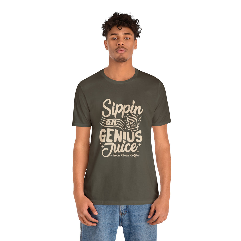 Adult man modeling an olive green short-sleeve T-shirt printed with the slogan “Sippin on Genius Juice” and a stylized coffee to-go cup graphic on the front, shown against a plain white background.