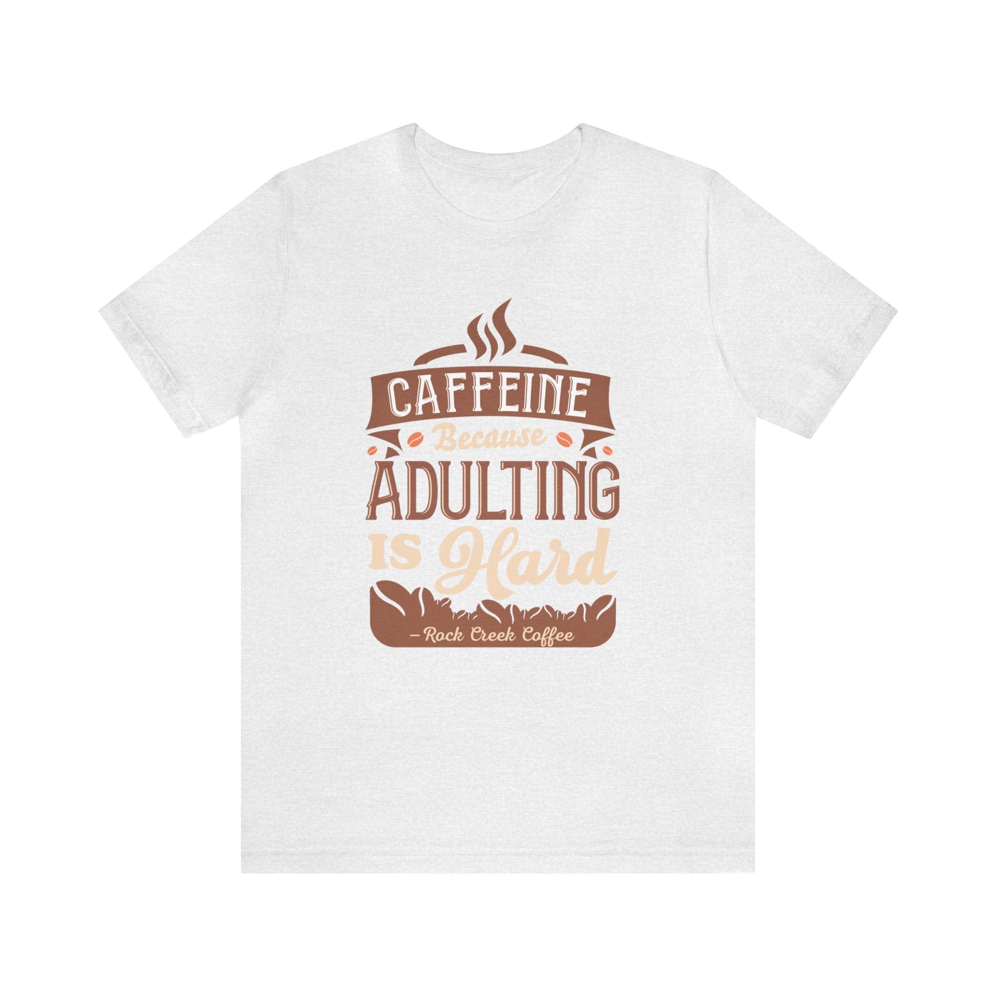 Ash short-sleeve T-shirt displayed flat against a plain white background, featuring the “Caffeine Because Adulting Is Hard” graphic in a stacked typographic design with Rock Creek Coffee branding below.
