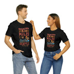 Adult man and woman modeling matching black short-sleeve T-shirts printed with a colorful graphic that reads “Roasted 818 Miles East of Seattle,” featuring a steaming coffee cup and mountain lake illustration, shown against a plain white background.