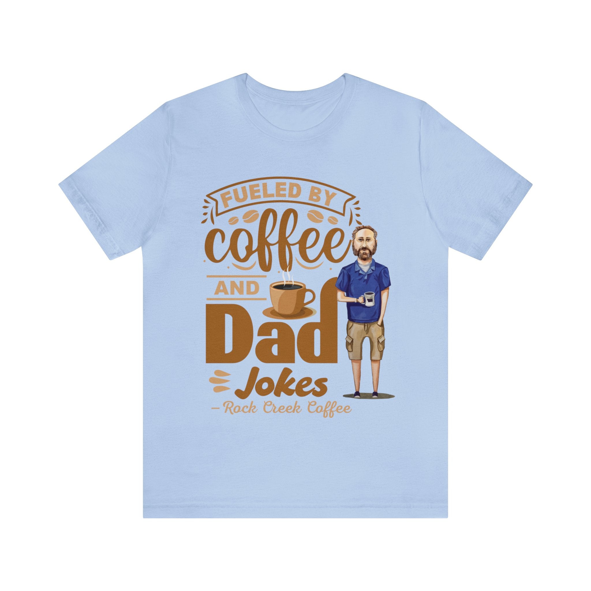 Light blue short-sleeve T-shirt laid flat on white background showing a coffee-themed graphic that reads “Fueled by Coffee and Dad Jokes” alongside a stylized coffee cup and bearded cartoon dad holding a mug.