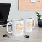 Two white Rock Creek Coffee mugs with “Around the Corner from Ordinary” design in gold and cream lettering displayed on a desk with a laptop, binder clips, stacked books, and a small potted plant in the background.