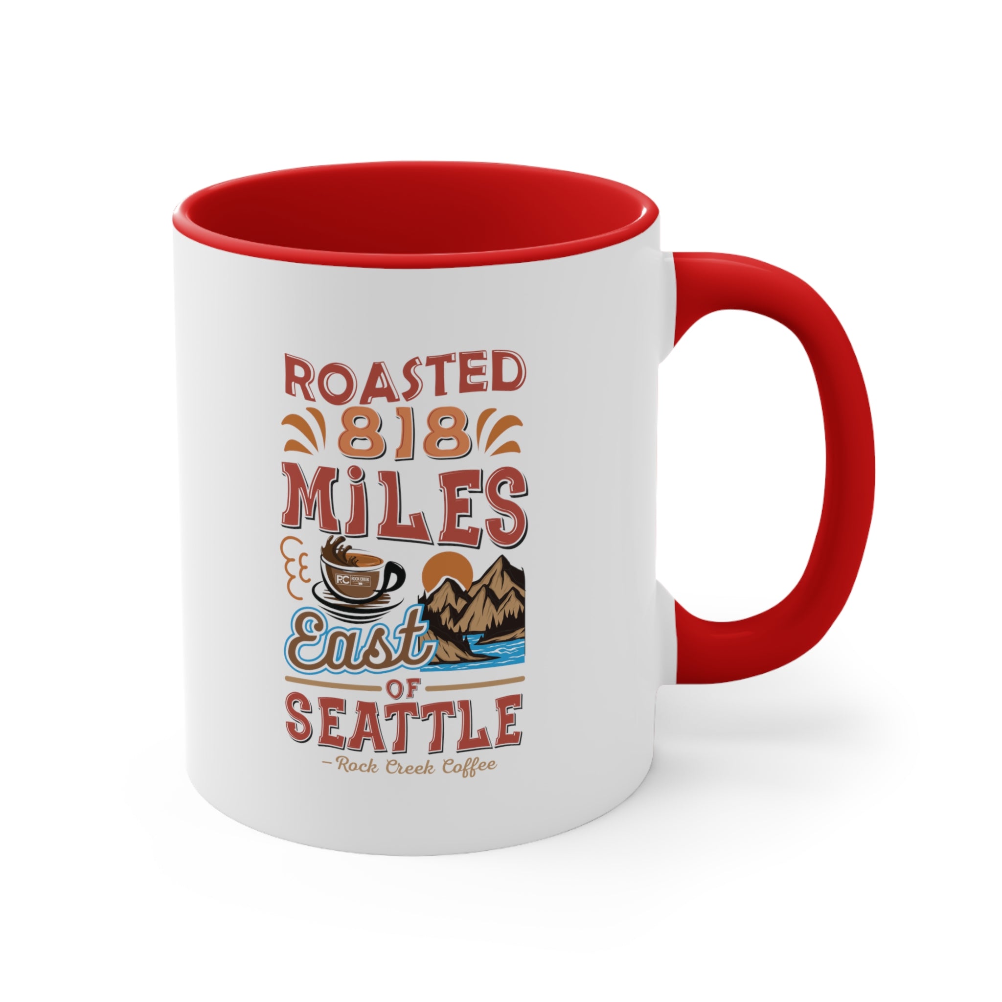 White ceramic coffee mug with a red interior and handle featuring the Roasted 818 Miles East of Seattle Rock Creek Coffee design in red, blue, and brown lettering with a coffee cup and mountain illustration.