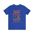 Royal blue Seattle coffee graphic T-shirt with “Roasted 818 Miles East of Seattle” print and scenic coffee illustration, shown on a white background.