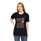 Adult woman modeling a black short-sleeve T-shirt printed with the “Sippin on Genius Juice” graphic in bold coffee-inspired lettering with a small mug illustration, shown against a plain white background.