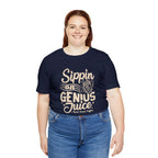 Smiling woman modeling a navy short-sleeve T-shirt printed with the slogan “Sippin on Genius Juice” and a stylized coffee to-go cup graphic on the front, shown against a plain white background.