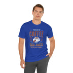 Adult man posing with one hand in his pocket while modeling a royal blue short-sleeve T-shirt featuring the “Fueled by Coffee and Dad Jokes” graphic with a coffee cup illustration and Rock Creek Coffee text, shown against a plain white background.