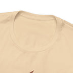Close-up detail of a soft cream crew neck T-shirt showing the neckline, collar stitching, and upper chest area, with only a small portion of the front graphic visible at the bottom edge against a plain white background.
