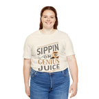 Adult woman smiling while wearing a cream short-sleeve T-shirt printed with the “Sippin on Genius Juice” graphic in large coffee-inspired lettering, photographed against a plain white background.