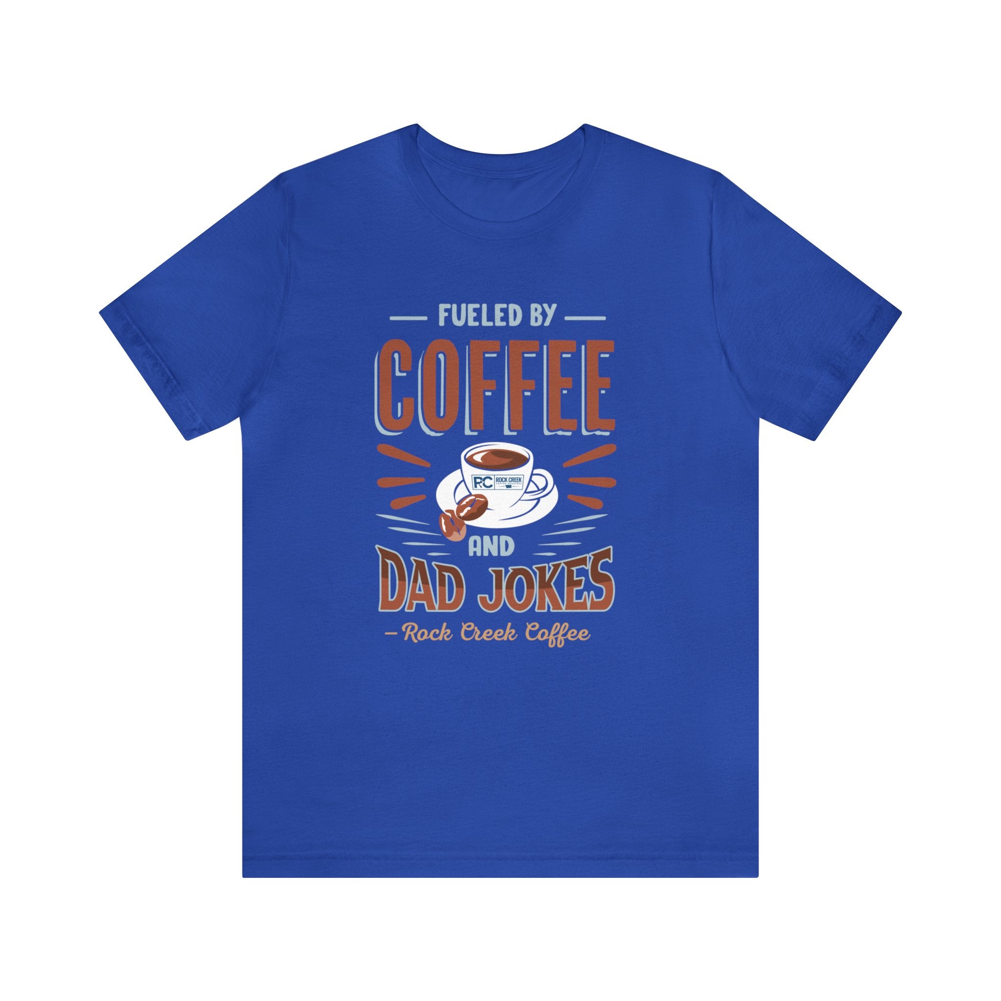 Royal blue short-sleeve T-shirt displayed flat against a plain white background, featuring a bold “Fueled by Coffee and Dad Jokes” graphic with a coffee cup illustration and Rock Creek Coffee text below.