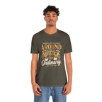 Adult man modeling an army green short-sleeve T-shirt featuring the phrase “Around the Corner from Ordinary” in a bold coffee-themed typographic design, shown against a plain white background.