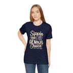 Smiling woman modeling a navy short-sleeve T-shirt printed with the slogan “Sippin on Genius Juice” and a stylized coffee to-go cup graphic on the front, shown against a plain white background.
