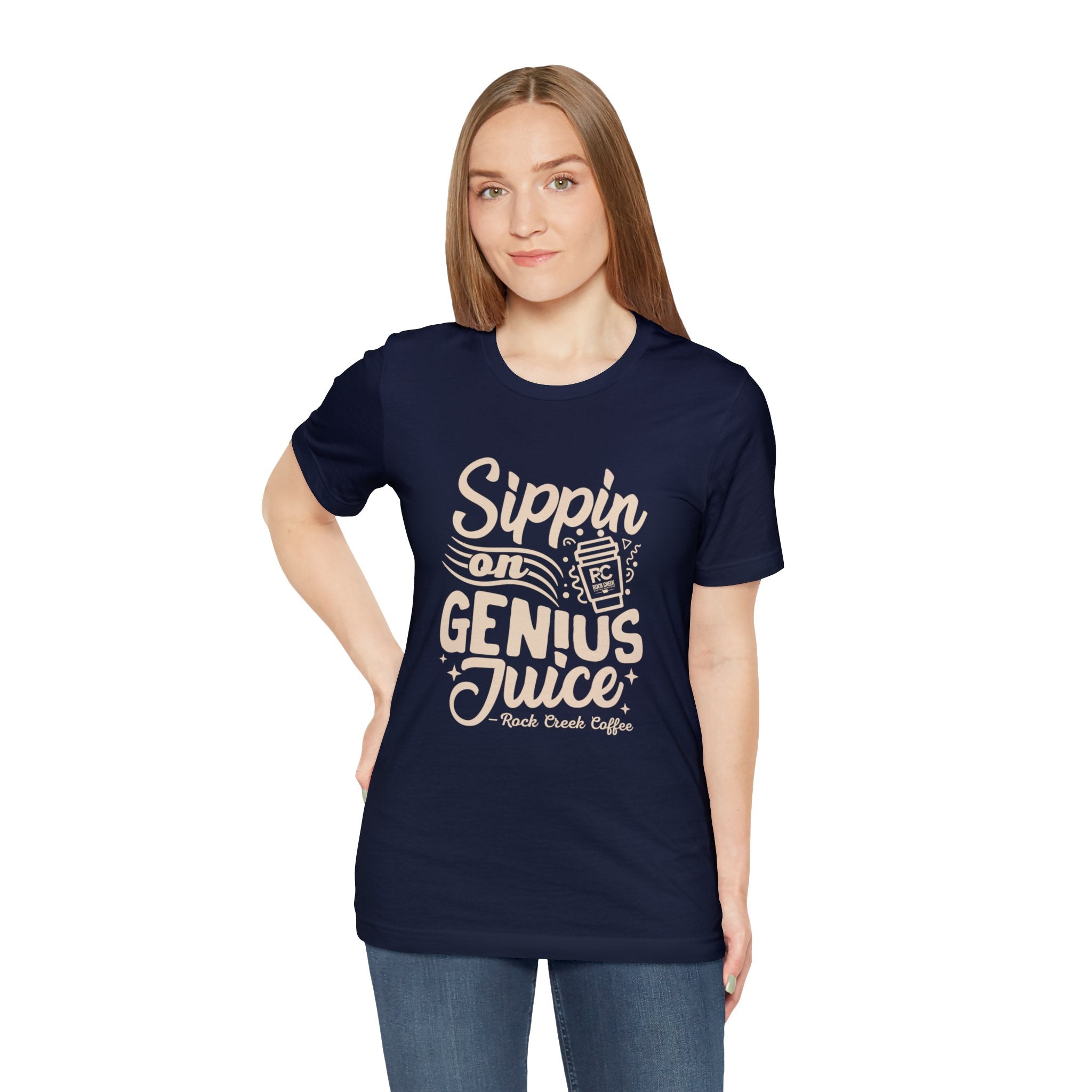 Smiling woman modeling a navy short-sleeve T-shirt printed with the slogan “Sippin on Genius Juice” and a stylized coffee to-go cup graphic on the front, shown against a plain white background.