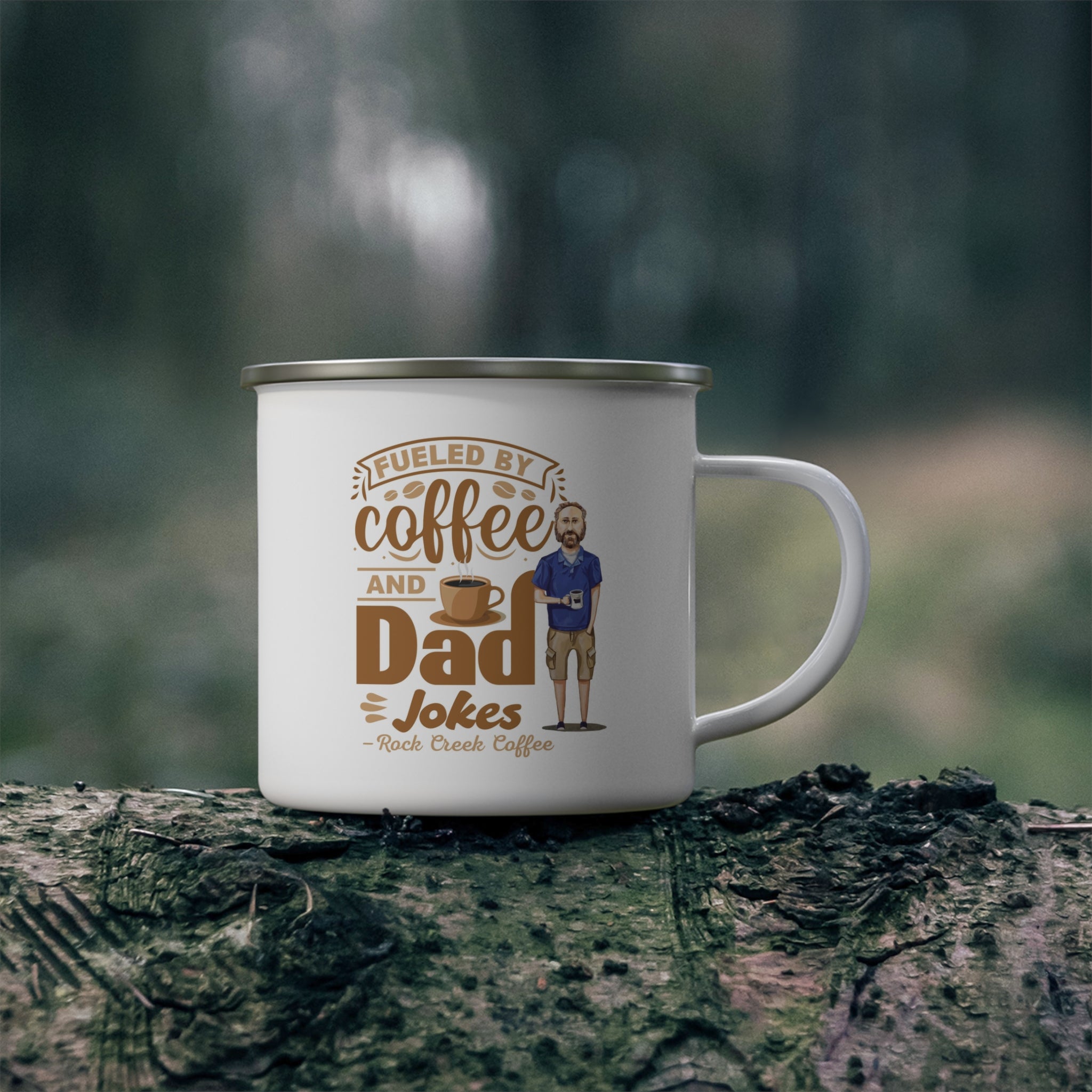 White enamel style coffee mug with silver rim and handle featuring the phrase Fueled by Coffee and Dad Jokes Rock Creek Coffee in brown lettering with a coffee cup graphic and illustration of a bearded dad holding a mug, placed on a mossy log outdoors with a blurred forest background.