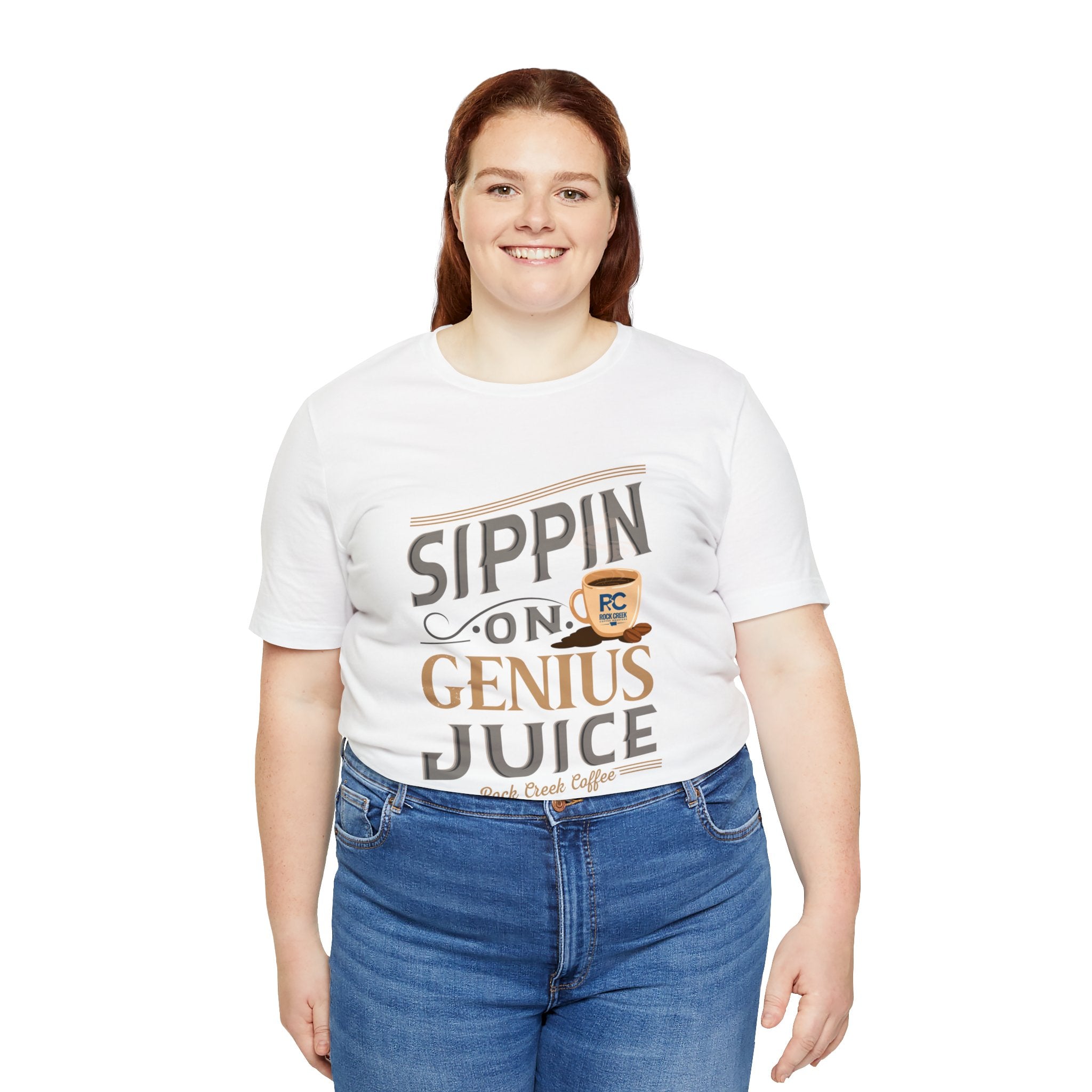 Adult woman smiling while modeling a white short-sleeve T-shirt featuring the “Sippin on Genius Juice” graphic in bold coffee-inspired lettering with a small mug illustration, shown against a plain white background.