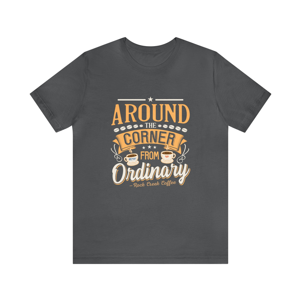 Asphalt gray short-sleeve T-shirt displayed flat against a plain white background, featuring the phrase “Around the Corner from Ordinary” in a bold coffee-themed typographic design with Rock Creek Coffee branding below.