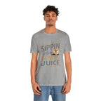 Adult man modeling a heather gray short-sleeve T-shirt featuring the “Sippin on Genius Juice” graphic in bold coffee-inspired lettering with a small cup illustration, shown against a plain white background.