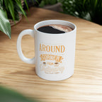 White Rock Creek Coffee mug with “Around the Corner from Ordinary” design in gold and cream lettering, filled with freshly brewed coffee and placed on a wooden table with green plants in the background.