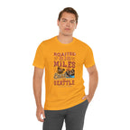 Adult man modeling a golden yellow short-sleeve T-shirt printed with a colorful graphic that reads “Roasted 818 Miles East of Seattle,” featuring a steaming coffee cup and mountain lake illustration, shown against a plain white background.