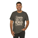 Smiling man modeling an olive green short-sleeve T-shirt with a coffee-themed slogan reading “Sippin on Genius Juice” and a stylized to-go cup graphic on the front, shown against a plain white background.