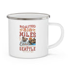 White enamel-style coffee mug with silver rim and handle featuring a colorful “Roasted 818 Miles East of Seattle - Rock Creek Coffee” design with a coffee cup and mountain illustration, displayed against a white background.