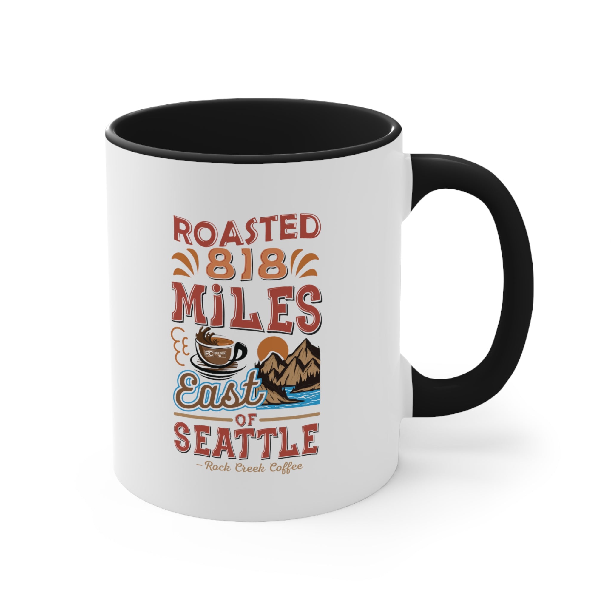White ceramic coffee mug with a black interior and handle featuring the Roasted 818 Miles East of Seattle Rock Creek Coffee design in red, blue, and brown lettering with a coffee cup and mountain illustration.