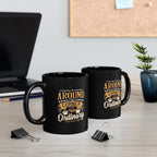 Two black ceramic coffee mugs featuring the Around the Corner from Ordinary Rock Creek Coffee design in gold and white lettering, displayed on a desk with a laptop, binder clips, notebook, and a small potted plant in the background.